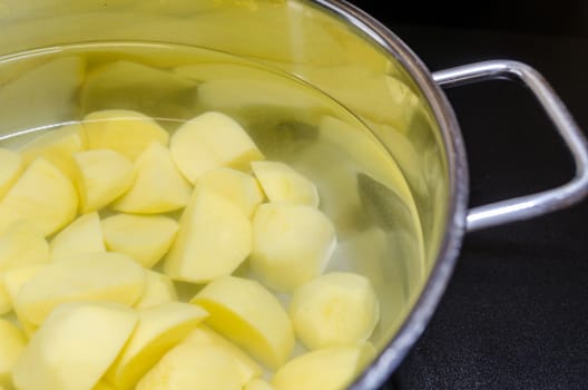 Pot with potatoes and water filled on a ceramic hob.