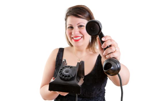 Friendly smiling attractive woman holding out an old fashioned land line telephone instrument - a call for you sir - in a service or hostess concept, isolated on white