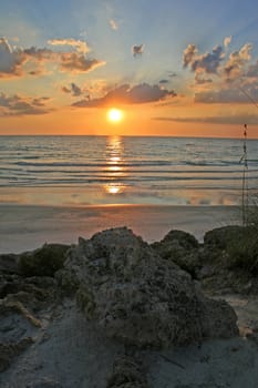 A sunset over the ocean with rocks