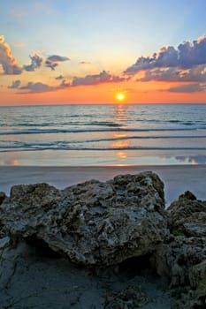 A sunset over the ocean with rocks