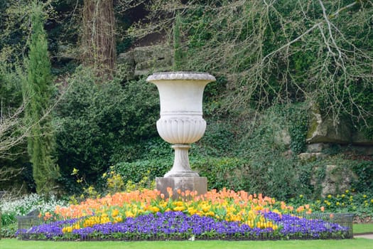 Large outdoor pot in classical garden with flowers