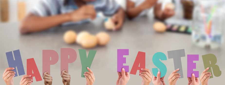 Hands holding up happy easter against concentrated siblings painting eggs 