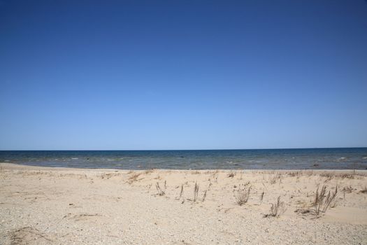 Waves reach long sandy shoreline beach of Great Lake Huron in Michigan.