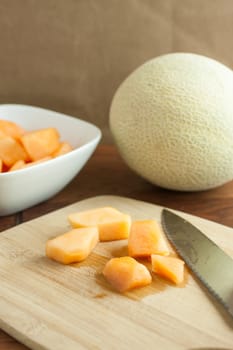 Fresh Cantalope on a cutting board and in a white bowl.