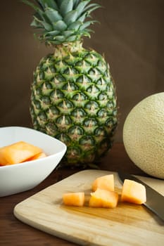 Cantalope and pinapple on a counter in the morning sun.