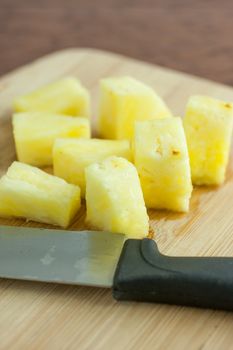 Fresh pineapple chunks on a bamboo cutting board, lite by the early morning sunlight.