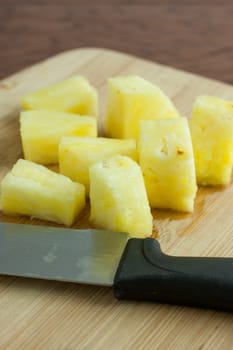 Fresh pineapple chunks on a bamboo cutting board, lite by the early morning sunlight.