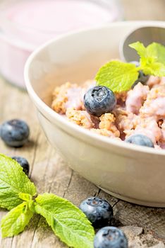 Fresh blueberry yogurt with granola and mint on a background