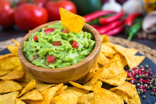 Guacamole in Wooden Bowl with Tortilla Chips and Ingredients