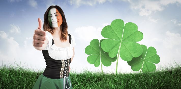 Irish girl showing thumbs up against field of grass under blue sky