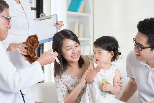 Child vaccination. Family doctor vaccines or injection to baby girl. Pediatrician and patient.