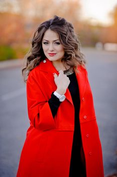 beautiful girl in red coat standing on the road.