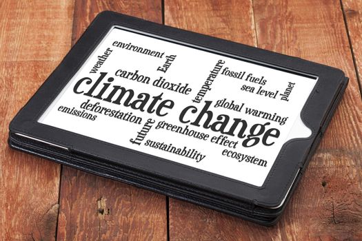 climate change word cloud on a digital tablet against rustic barn wood