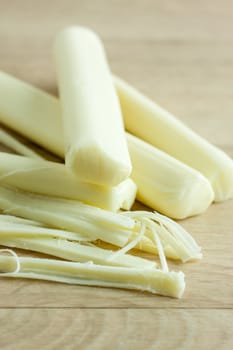 Sticks of mozzerella string cheese on a light colored table top.