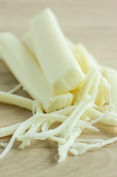 Sticks of mozzerella string cheese on a light colored table top.