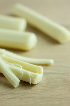 Sticks of mozzerella string cheese on a light colored table top.