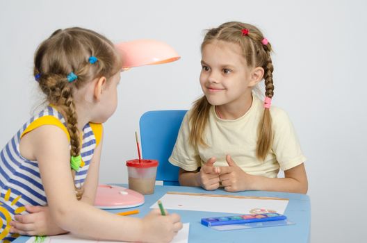 Two girls of four and six years of sitting at the table and draws and paints and pencils