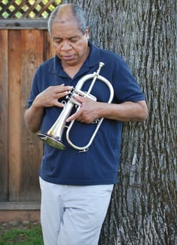 African american jazz musician with his flugelhorn outside.