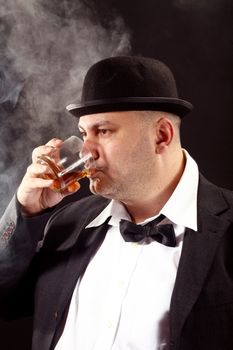 man with a bowler hat and bow tie drink whiskey