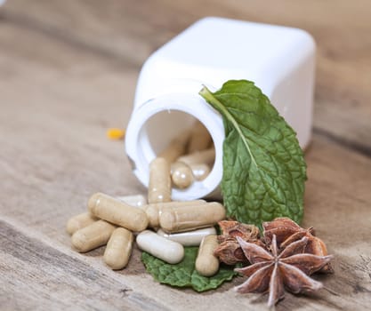 Mint leaf and Herb capsule spilling out of a bottle
