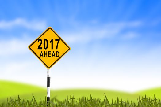 2017, Road sign in the grass field to new year and blue sky, can use as abstract background