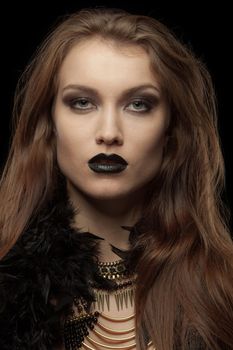Closeup portrait of a gothic femme fatale with black lips on black background