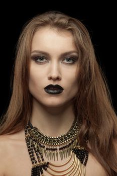 Closeup portrait of a gothic young woman with black lips on black background