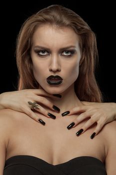 Closeup portrait of a pretty gothic woman with hands of vampire on her neck on black background