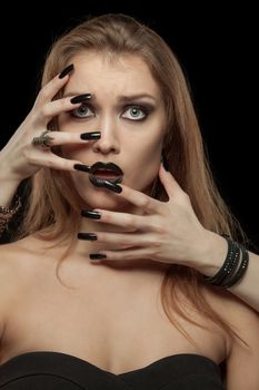 Portrait of a gothic woman with hands of vampire on her face on black background. Halloween