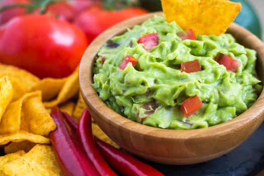 Guacamole in Wooden Bowl with Tortilla Chips and Ingredients