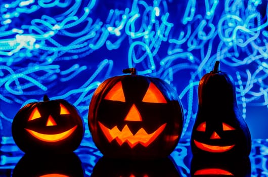 Closeup of scary Halloween pumpkins with lanterns on blue background