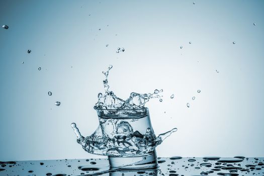 ice cube falling into a glass of water on blue background