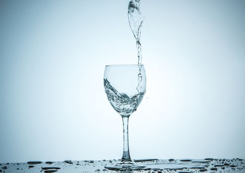 A glass being filled with water on white background