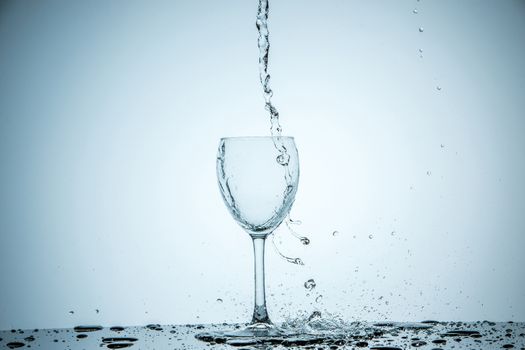 A glass being filled with water on white background