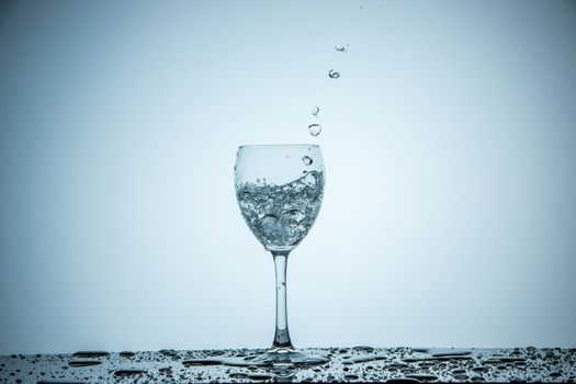 A glass being filled with water on white background