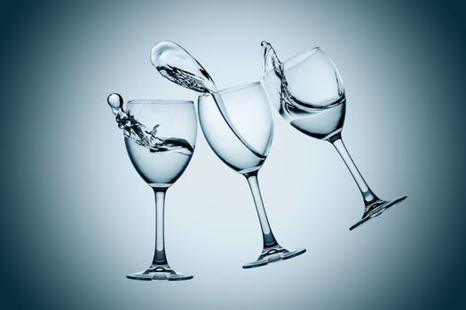 Three water glasses splash on gray background