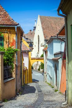 Sighisoara, Romania - June 23, 2013: Old stone paved street with tourists from Sighisoara fortress, Transylvania, Romania