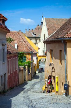 Sighisoara, Romania - June 23, 2013: Old stone paved street with tourists from Sighisoara fortress, Transylvania, Romania