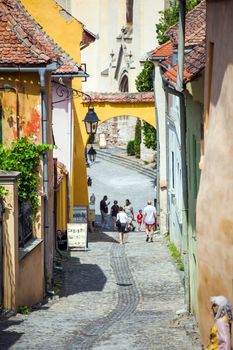 Sighisoara, Romania - June 23, 2013: Old stone paved street with tourists from Sighisoara fortress, Transylvania, Romania