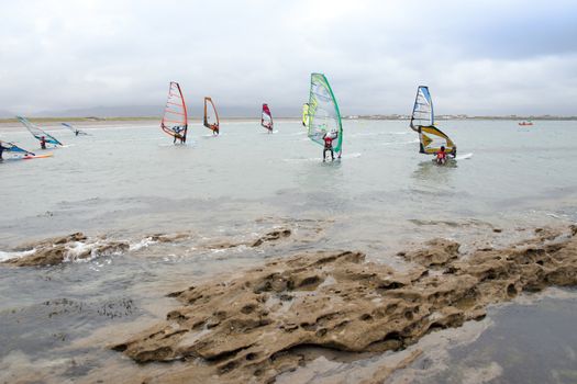 wind surfers racing in the storm winds on the wild atlantic way in county Kerry Ireland near rocks