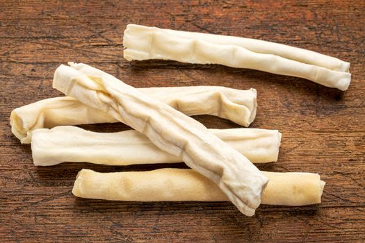 small rawhide bones - dog treats on grunge wood background