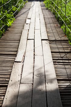 Suspension Bridge made of wood. Walking through the trees above a waterfall below.