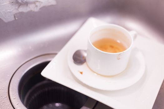 Coffee cup and white plates. Lay piled in the sink in the kitchen....