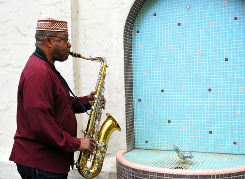 Muslim jazz musician performing on his saxophone outside.