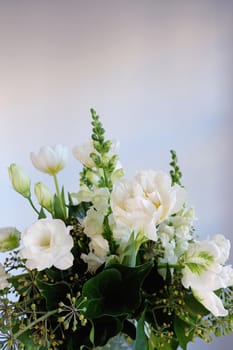 Bouquet of white and green flowers against a white wall