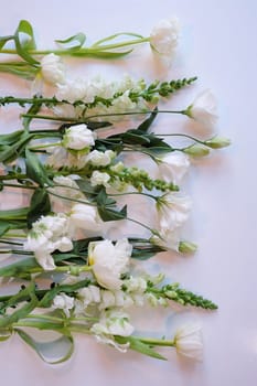 Assorment of white and green flowers laid out in a row on a white surface 