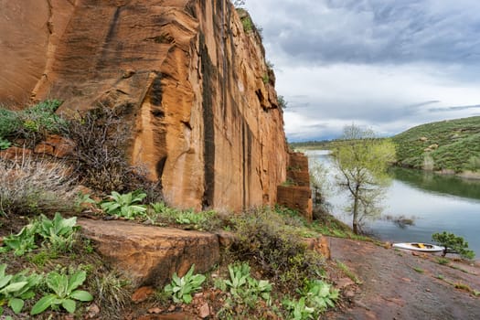 rocky shore and canoe - old sandstone quarry and white canoe or kayak on the shore of Horsetooth Reservoir near Fort Collins, Colorado