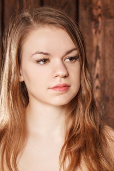 Portrait of a girl on a background of a wooden wall