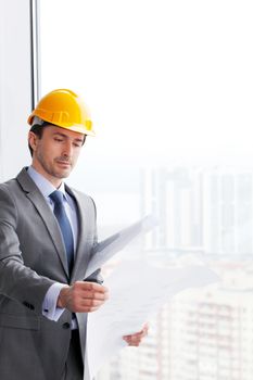 businessman in construction helmet looking at blueprint