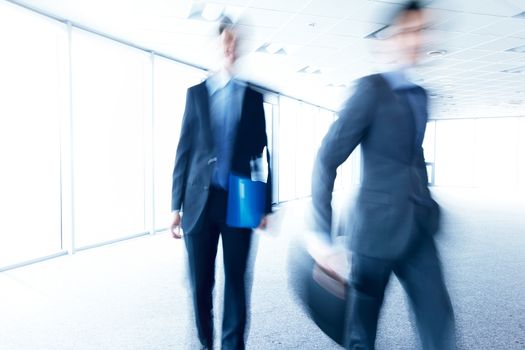 business men walking through office blurred